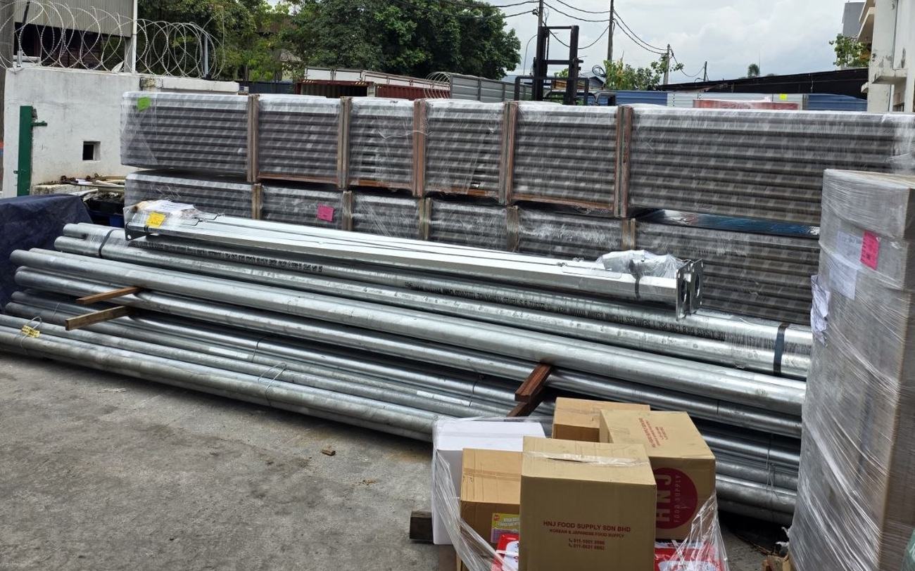 Galvanised steel pipes and stacked roofing sheets banded and wrapped in the yard, ready for shipment to East Malaysia